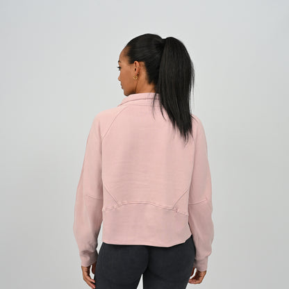 Back view of model wearing the dusty pink Hybryd Monterey half zip sweatshirt showing ribbed panel construction