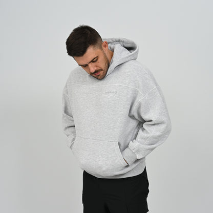 Three-quarter angle of male model wearing the grey Hybryd Palmer drop shoulder hoodie looking down