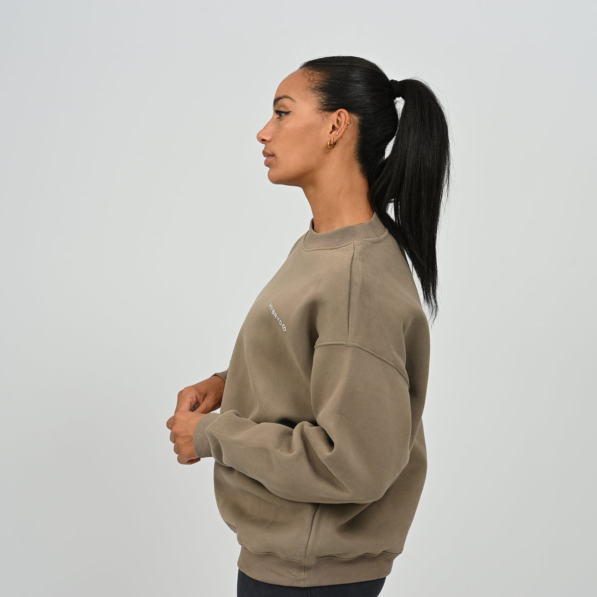 Side profile shot of female model wearing the khaki Women's Jasper fleece-lined relaxed crew neck sweater.
